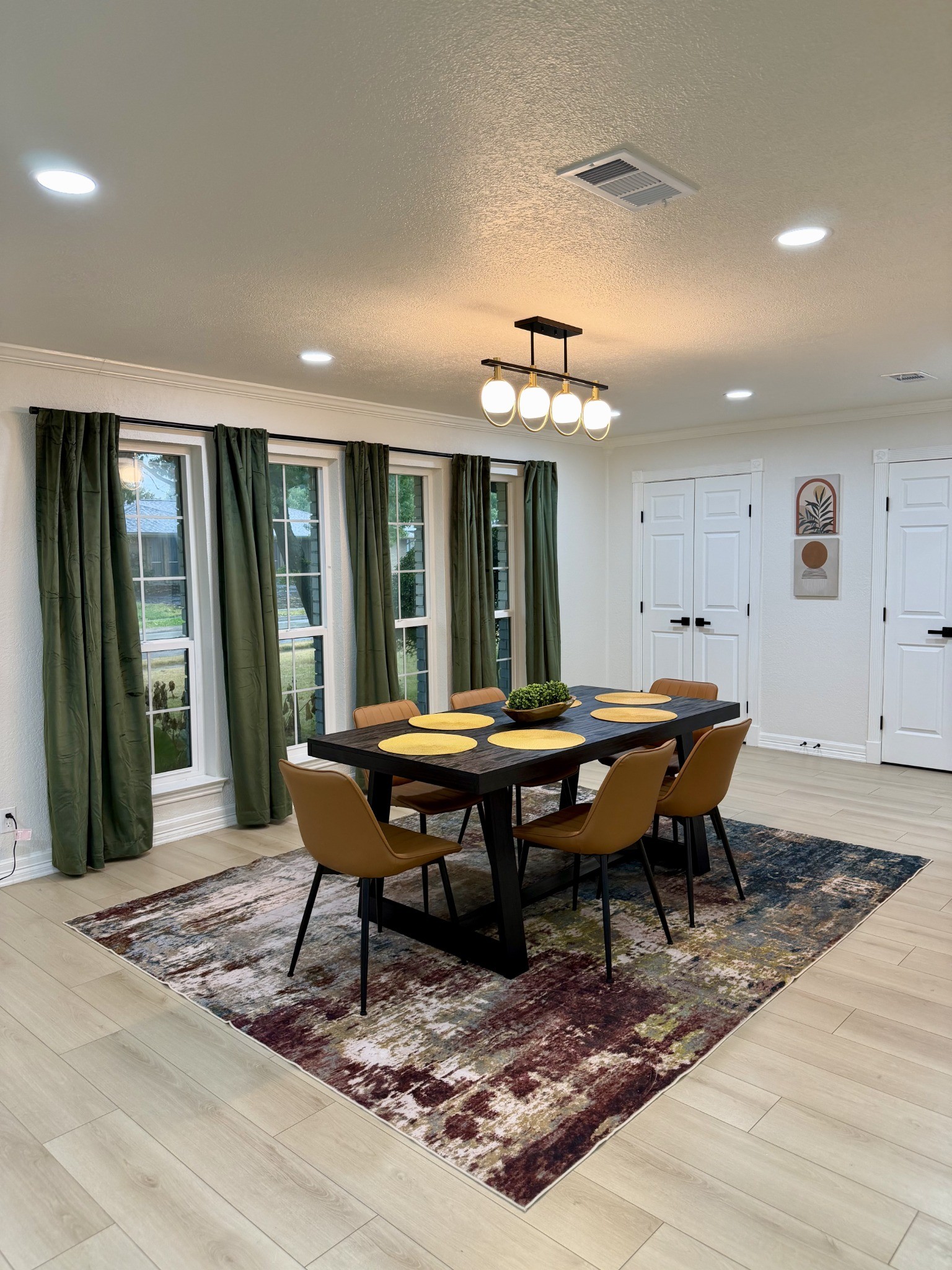 Dining room with cognac chairs, green curtains and seating for six